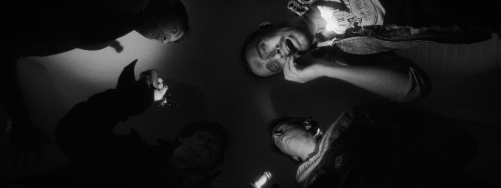 Group of people gather in a circle looking down, black and white