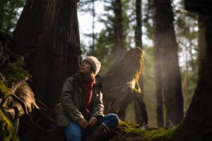 A girl by a tree in sunlit forest