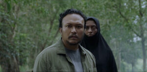 A man and women in religious headdress look towards the camer