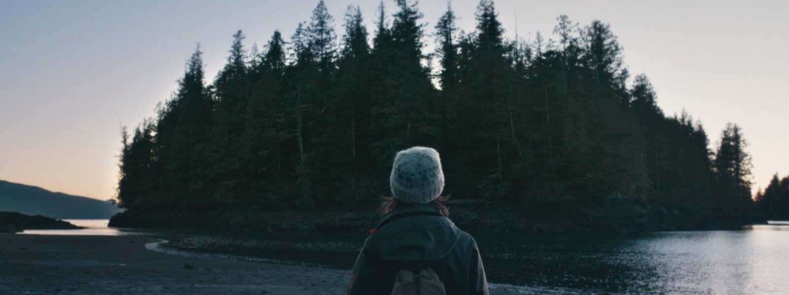 A girl watches a tree covered island