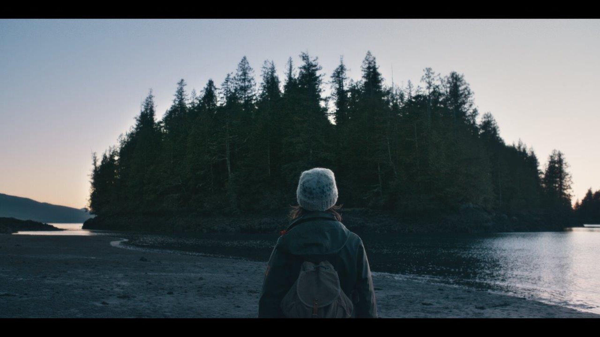 A girl watches a tree covered island