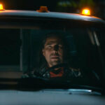 Two rugged looking men in the front seats of a pick-up truck, at night.