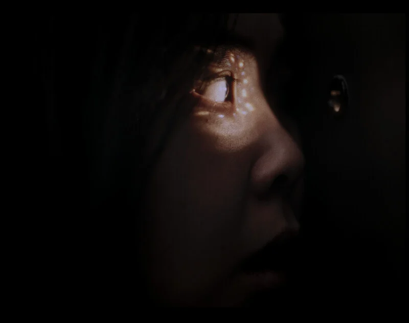 A girl looks through a hole in the door.